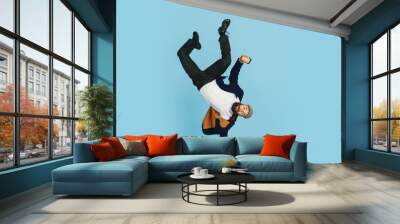 Young caucasian businessman having fun dancing break dance on blue studio background. Management, flexible, freedom, professional occupation, alternative way of modern working. Loves his job Wall mural