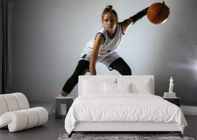 Young caucasian female basketball player of team in action, motion in run isolated on white wall background. Concept of sport, movement, energy and dynamic, healthy lifestyle. Training, practicing. Wall mural