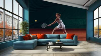 Young caucasian professional sportswoman playing tennis on sport court background. Training, practicing in motion, action. Power and energy. Movement, ad, sport, healthy lifestyle concept. Front view. Wall mural