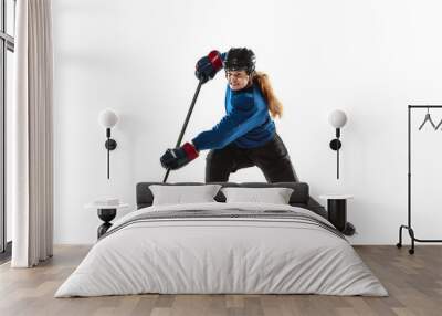 Young female hockey player with the stick on ice court and white background. Sportswoman wearing equipment and helmet training. Concept of sport, healthy lifestyle, motion, action, human emotions. Wall mural