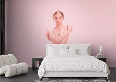 Young naked beautiful girl looking at camera isolated on pink studio background. Concept of beauty, purity, tenderness and grace. Wall mural