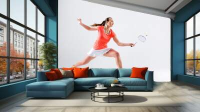 Young woman playing badminton over white background Wall mural