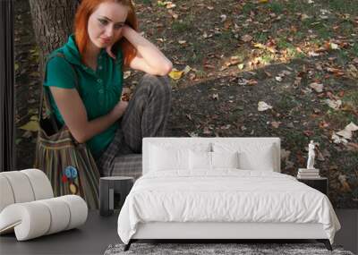 Redheaded girl sitting under the tree Wall mural