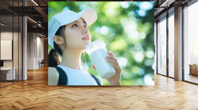 A beautiful Japanese woman is drinking water from the glass outdoors. Portrait. close up view Wall mural