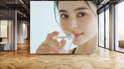 A beautiful Japanese woman is drinking water from the glass. Portrait. close up view Wall mural