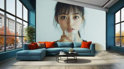 A beautiful Japanese woman is drinking water from the glass. Portrait. close up view Wall mural