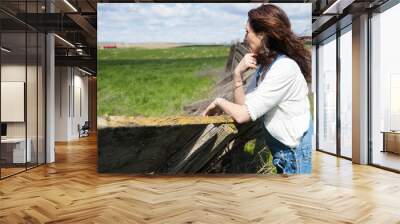 Pretty woman wearing overalls outside near a country field Wall mural