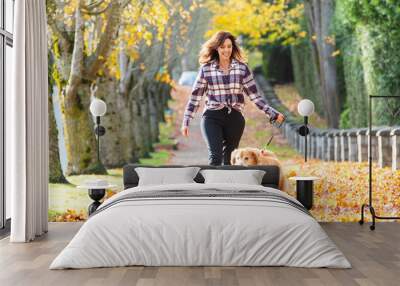 Woman walking golden retriever dog in Fall leaves Wall mural