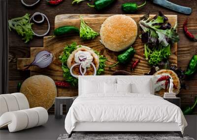 Chicken burgers with fresh salad, onion, peppers and mayonnaise sauce. Overhead view and dark, wooden background. Wall mural