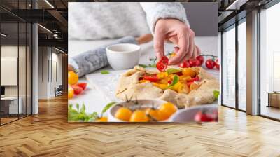 Women preparing tomatoes and basil galette on white table Wall mural