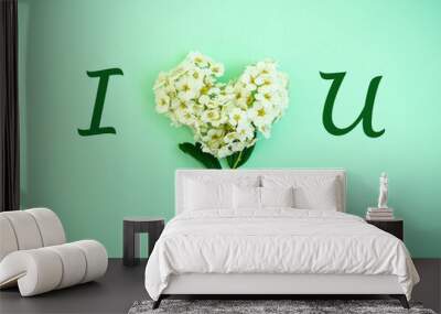 White spring flowers in a heart shape with I LOVE YOU letters on pastel mint green background. Natural minimal concept. Creative spring idea. Love design. Flat lay. Valentines idea. Wall mural