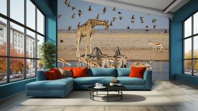 A gathering of african animals at a waterhole Wall mural