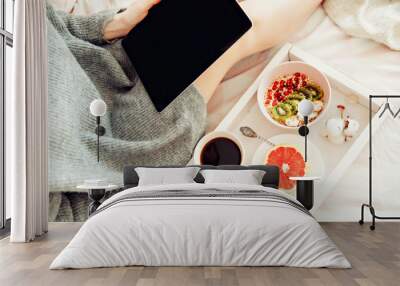 Breakfast and morning news- women reading morning news on her tablet in bed Wall mural