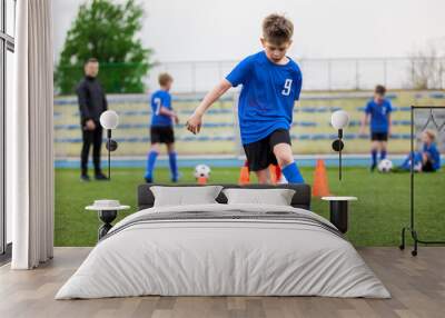 Boys attending soccer training on school field. Young man coaching children on physical education class. Soccer practice for children Wall mural