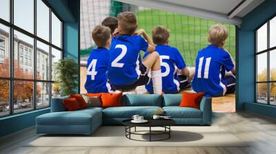 Children futsal team. Group of young indoor soccer players sitting together. Kids school football tournament Wall mural