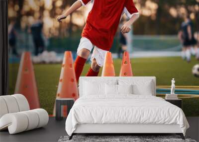 Soccer Drills: The Slalom Drill. Youth soccer practice drills. Young football player training on pitch. Soccer slalom cone drill. Boy in red soccer jersey shirt running with ball between cones Wall mural