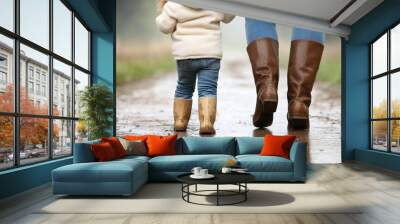 Child and adult walking on a muddy path, rear view Wall mural