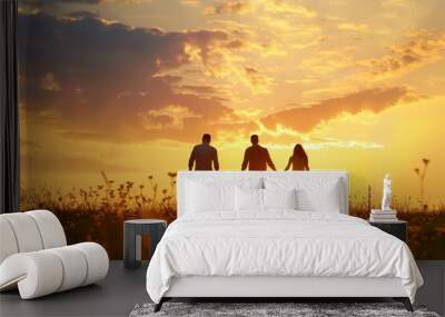 A family of four walks hand-in-hand towards the setting sun in a field of wildflowers Wall mural