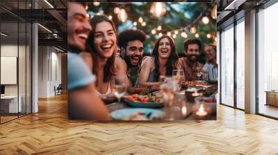 Friends laughing and sharing a meal together at an outdoor dinner party Wall mural