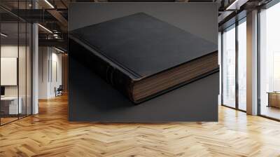 A closed, dark leather-bound book resting on a surface, suggesting a sense of mystery or knowledge. Wall mural