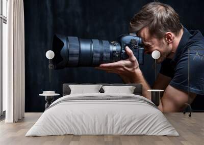 A photographer captures an image using a professional camera with a large lens, focused on the shot. Wall mural