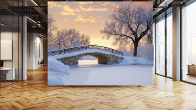 A serene winter landscape featuring a snow-covered bridge over a frozen river, illuminated by a colorful sunset. Wall mural