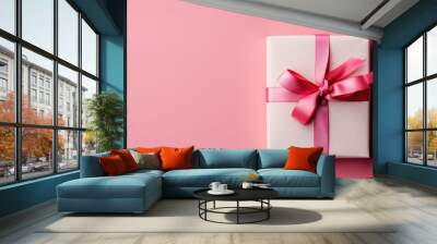 A simple yet elegant white gift box tied with a satin pink ribbon, centered on a matching pink background, conveying a sense of giving, celebration or surprise Wall mural