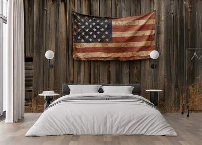 A weathered American flag hangs on a rustic wooden wall, surrounded by dry grass, evoking a sense of nostalgia and history. Wall mural