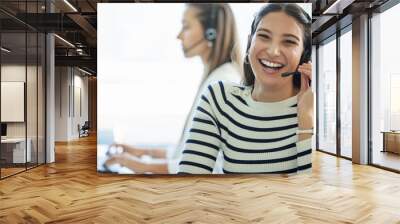 Shes having a good day. Shot of a young woman wearing a headset while working in a call center. Wall mural