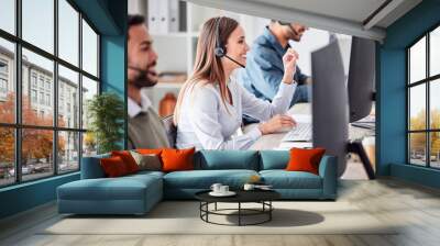 Call center, woman and working in team office with headset, computer and online customer support, service or help. Businesswoman, smile and contact us, crm and telemarketing employee talking Wall mural