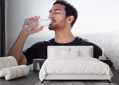 Stay hydrated. Cropped shot of a handsome young male athlete hydrating during his workout on the beach. Wall mural