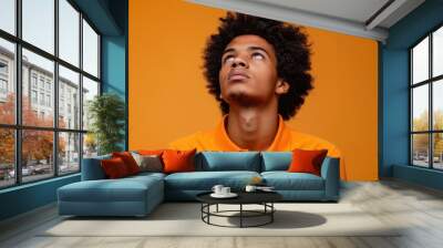 Curly-Haired Brown Man Looking Up: Curly-haired man, looking up, orange background Wall mural