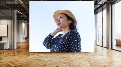 Asian woman gazing out against a plain clear sky. Optimistic, hopeful, youthful concept. Wall mural