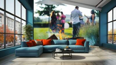 Smokey outdoor fire pit with people gathered together at a party restaurant function in the background Wall mural