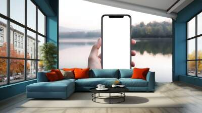 iPhone with transparent screen in hand mockup, lakeside scenery background Wall mural