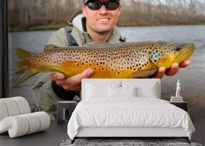 Fly fisherman holding a huge Brown Trout fish Wall mural