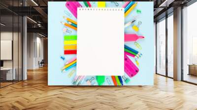 White notebook surrounded by various school office and painting supplies on blue background. Back to school concept. Top view. Copy space Wall mural