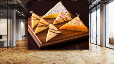 Assortment of cheese slices arranged on rustic wooden board for elegant presentation Wall mural