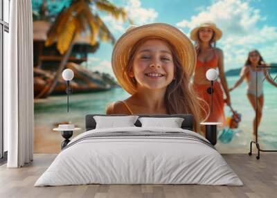 Young girl with long brown hair smiling at the camera. She is wearing an orange tank top and a straw hat. In the background, there is a beach scene with palm trees and a woman with an orange top.. Wall mural