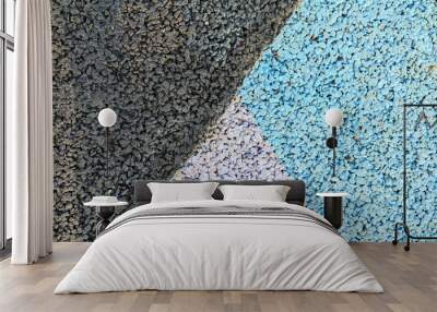 A close-up of a textured surface with sections of dark gray, light gray, and blue gravel creating an abstract pattern Wall mural