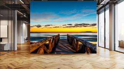 beautiful landscape with wooden walkway to seascape beach at sunrise with blue and orange sky and island in the background Wall mural