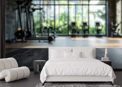 A blurred gym interior with workout equipment against large windows, showing a bright, modern fitness space. Wall mural