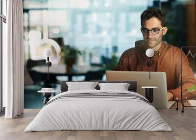 Businessman using a laptop while working late in his office Wall mural