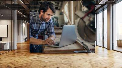 Carpenter working on a laptop in his woodworking studio Wall mural