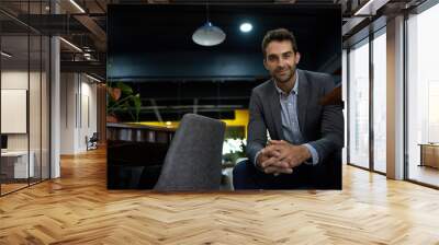 Confident young businessman sitting alone in an office after work Wall mural