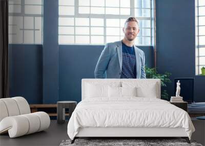 Confident young entrepreneur standing alone in a modern office Wall mural