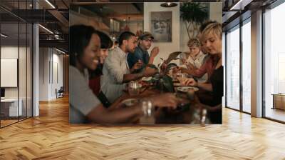 Diverse friends talking over a bistro dinner at night Wall mural