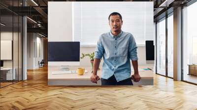 Focused Asian designer leaning on a desk in an office Wall mural