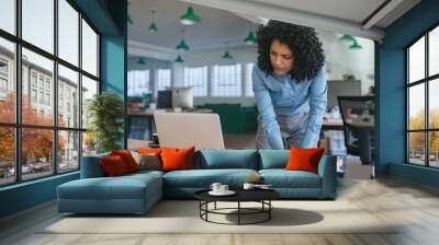 Focused young businesswoman standing at her office desk writing notes Wall mural