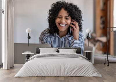 Laughing female entrepreneur talking with a client on her cellphone Wall mural